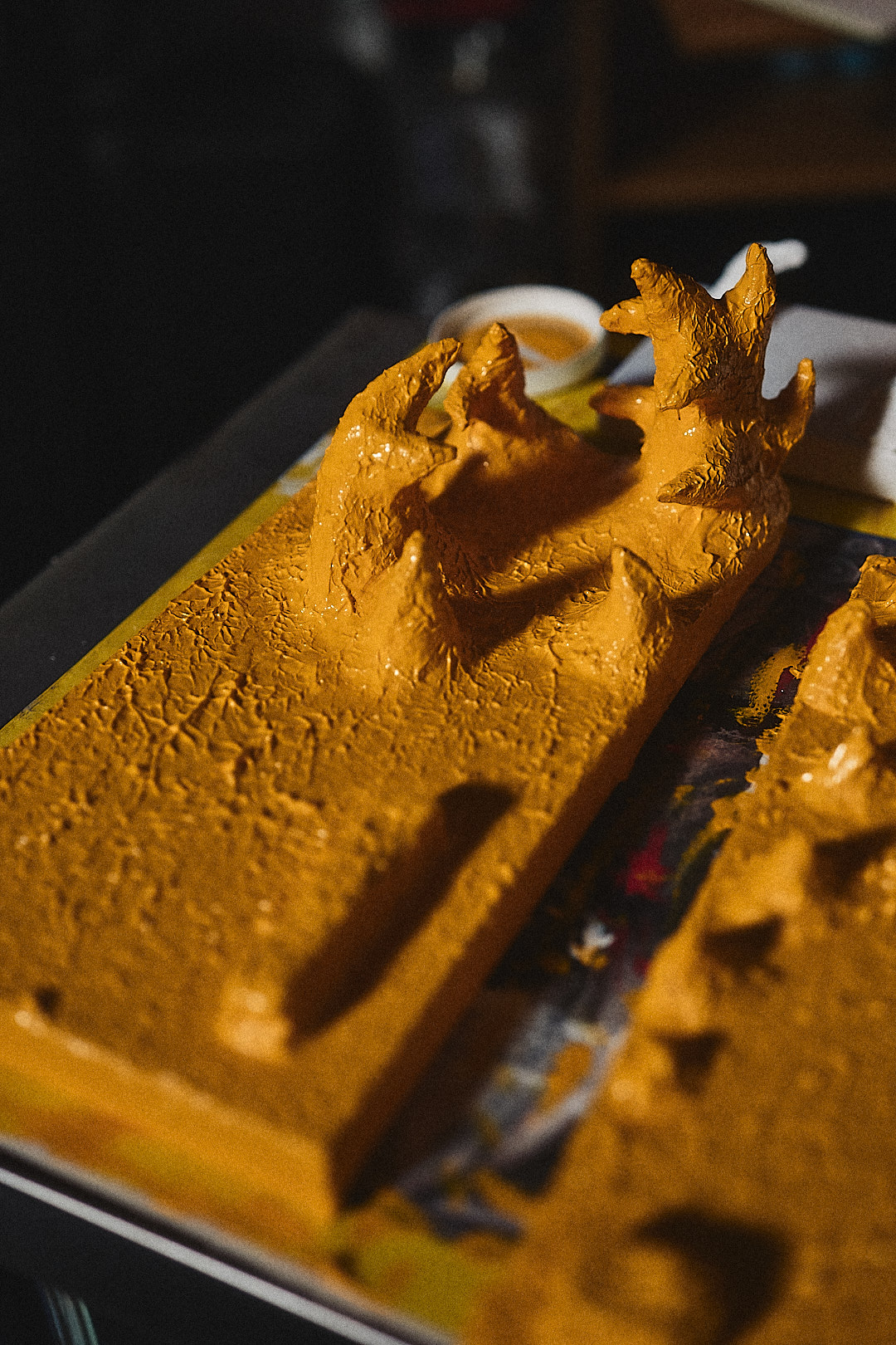 Close view of pointed sculptural forms receiving a yellow layer of paint.